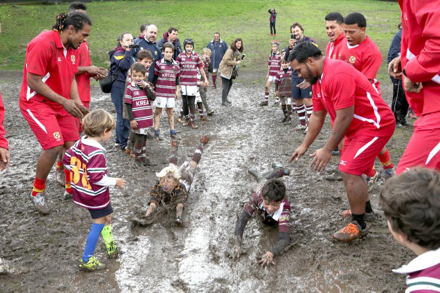 Encuentro de la Selección de Rugby de Tonga con las Escuelas de Rugby - Imagen de los niños de la escuela de rugby embarrados con miembros de la selección de Tonga.