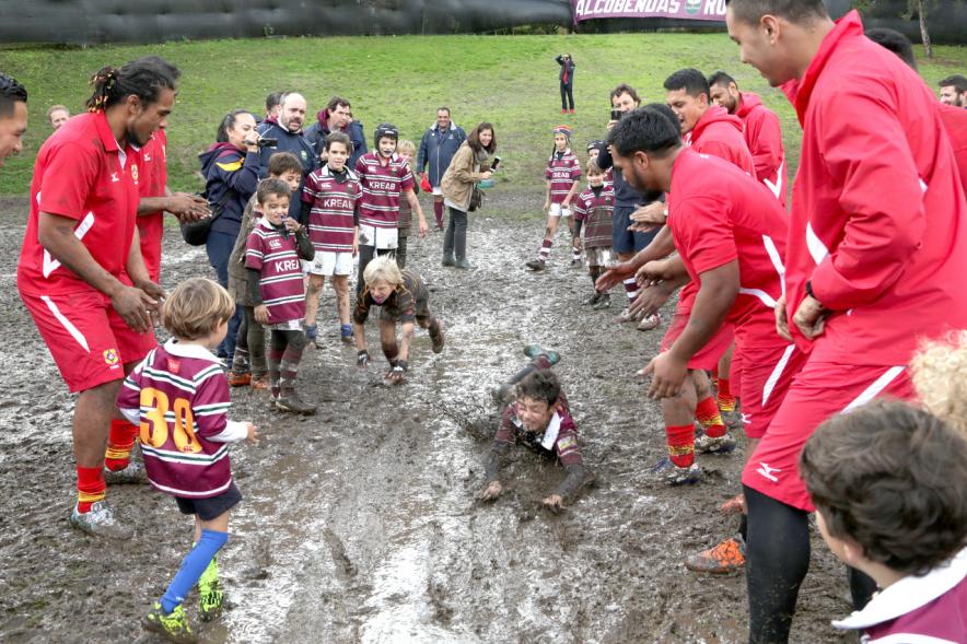 Encuentro de la Selección de Rugby de Tonga con las Escuelas de Rugby - Imagen de los niños de la escuela de rugby embarrados con miembros de la selección de Tonga.