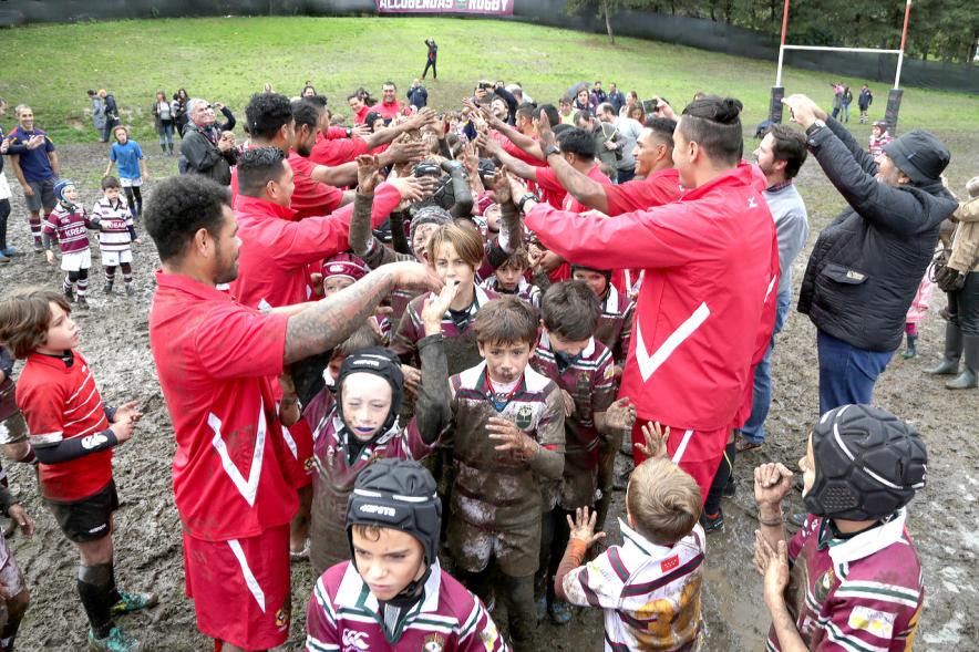 Encuentro de la Selección de Rugby de Tonga con las Escuelas de Rugby - Imagen de los niños de la escuela de rugby embarrados con miembros de la selección de Tonga.