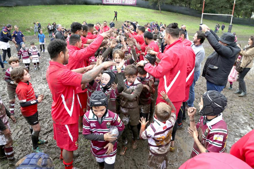 Encuentro de la Selección de Rugby de Tonga con las Escuelas de Rugby - Imagen de los niños de la escuela de rugby embarrados con miembros de la selección de Tonga.