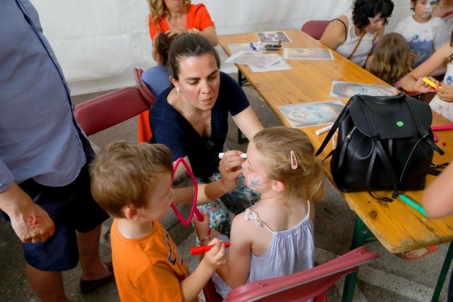 Noche de San Juan 2018 - Actividades y Hoguera de San Juan - Imagen de unos niños en un taller mientras la maquilla una monitora.