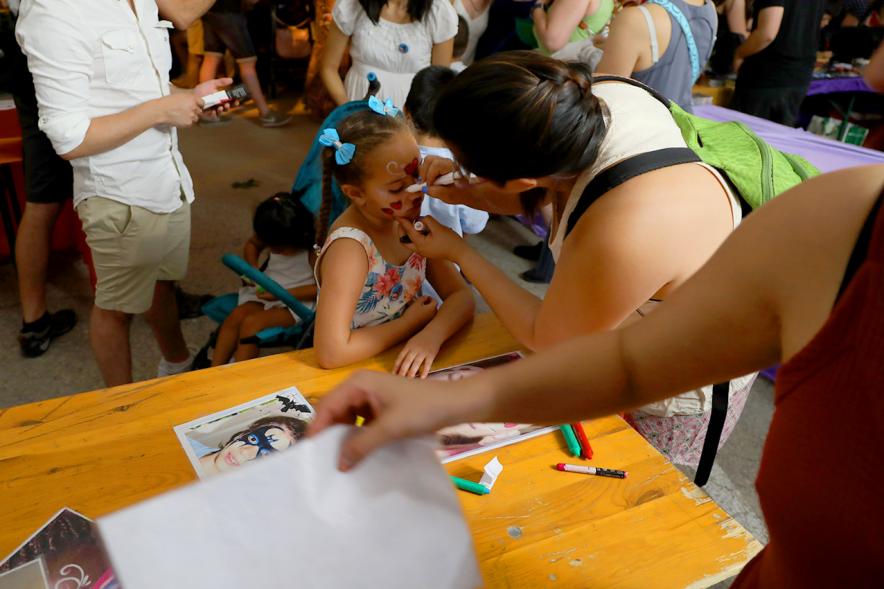 Noche de San Juan 2018 - Actividades y Hoguera de San Juan - Imagen de una niña en un taller mientras la maquilla una monitora.