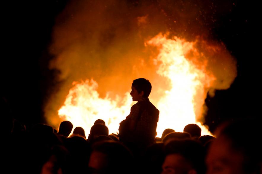 Noche de San Juan 2018 - Actividades y Hoguera de San Juan - Imagen de la llamas de la hoguera y los perfiles de personas alrededor del fuego.