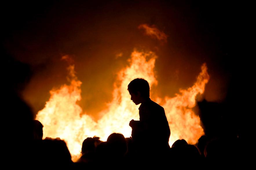 Noche de San Juan 2018 - Actividades y Hoguera de San Juan - Imagen de la llamas de la hoguera y los perfiles de personas alrededor del fuego.