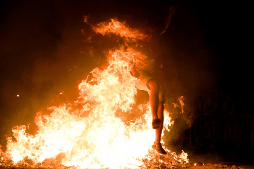 Noche de San Juan 2018 - Actividades y Hoguera de San Juan - Imagen de una gran llama de la hoguera y una persona saltándola.
