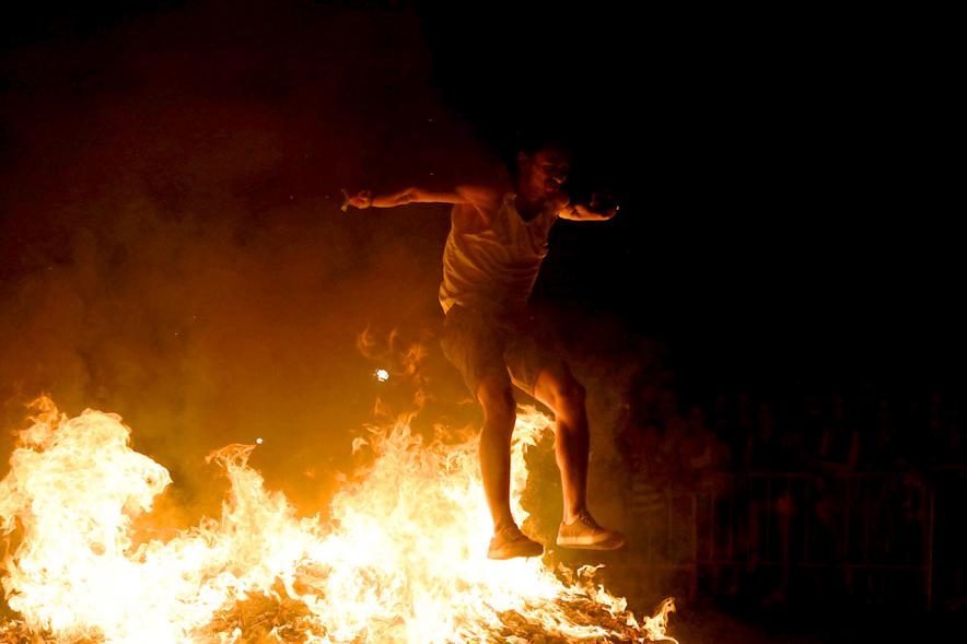 Noche de San Juan 2018 - Actividades y Hoguera de San Juan - Imagen de una gran llama de la hoguera y una persona saltándola.