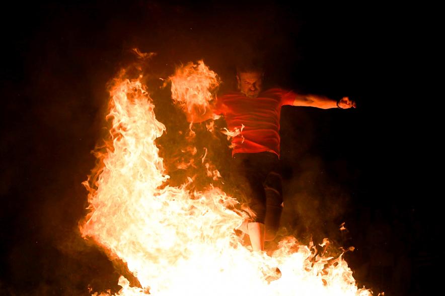 Noche de San Juan 2018 - Actividades y Hoguera de San Juan - Imagen de una gran llama de la hoguera y una persona saltándola.