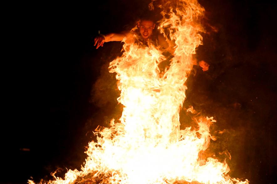 Noche de San Juan 2018 - Actividades y Hoguera de San Juan - Imagen de una gran llama de la hoguera y una persona saltándola.