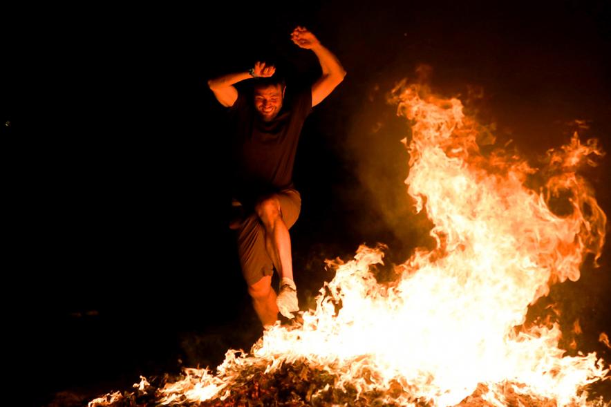 Noche de San Juan 2018 - Actividades y Hoguera de San Juan - Imagen de una gran llama de la hoguera y una persona saltándola.