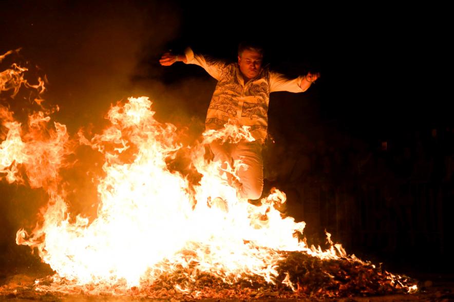 Noche de San Juan 2018 - Actividades y Hoguera de San Juan - Imagen de una gran llama de la hoguera y una persona saltándola.