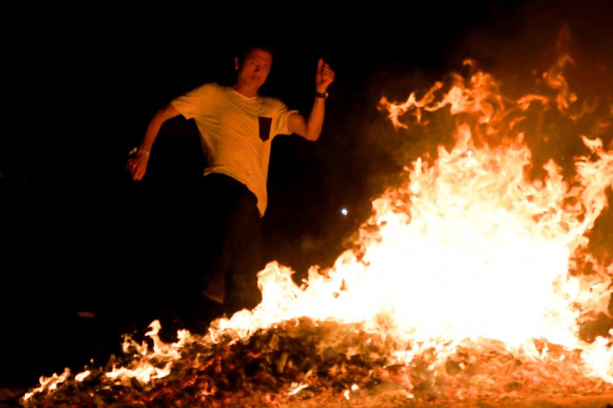 Noche de San Juan 2018 - Actividades y Hoguera de San Juan - Imagen de una gran llama de la hoguera y una persona saltándola.