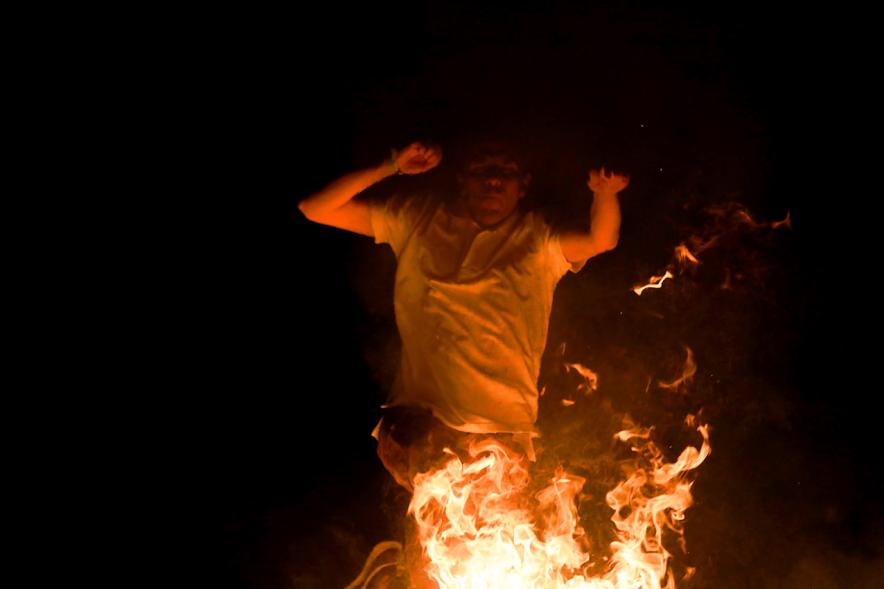 Noche de San Juan 2018 - Actividades y Hoguera de San Juan - Imagen de una gran llama de la hoguera y una persona saltándola.
