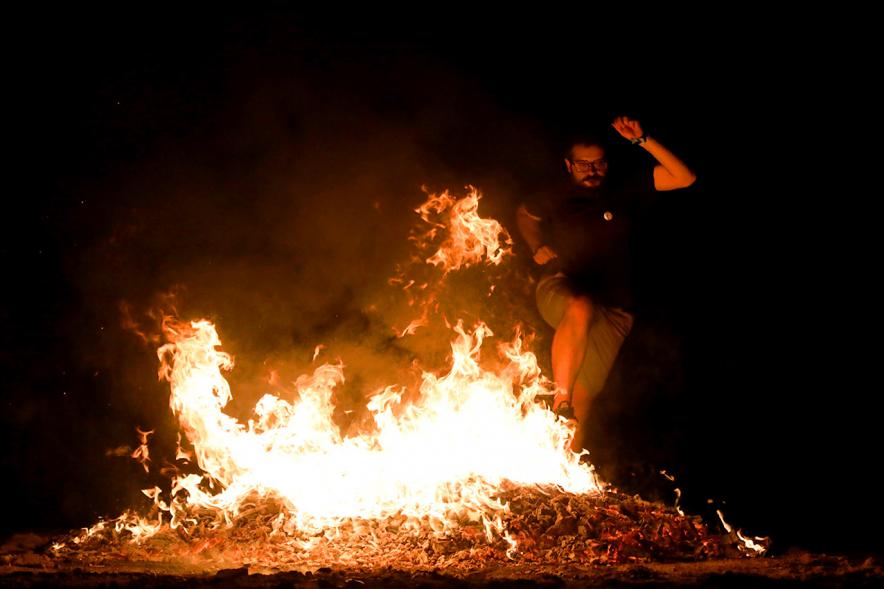 Noche de San Juan 2018 - Actividades y Hoguera de San Juan - Imagen de una gran llama de la hoguera y una persona saltándola.