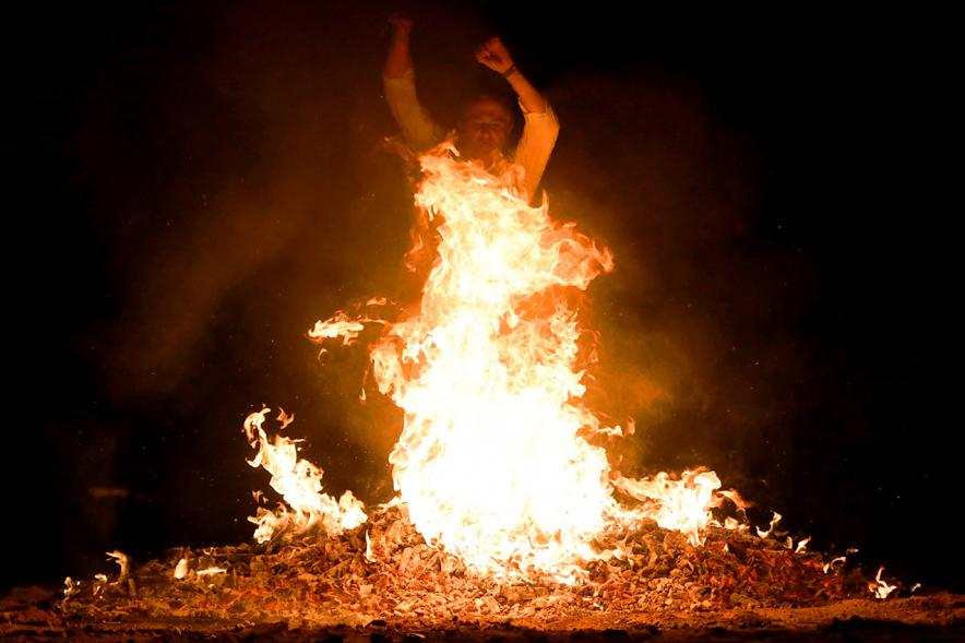 Noche de San Juan 2018 - Actividades y Hoguera de San Juan - Imagen de una gran llama de la hoguera y una persona saltándola.