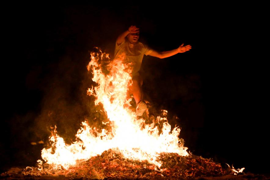 Noche de San Juan 2018 - Actividades y Hoguera de San Juan - Imagen de una gran llama de la hoguera y una persona saltándola.