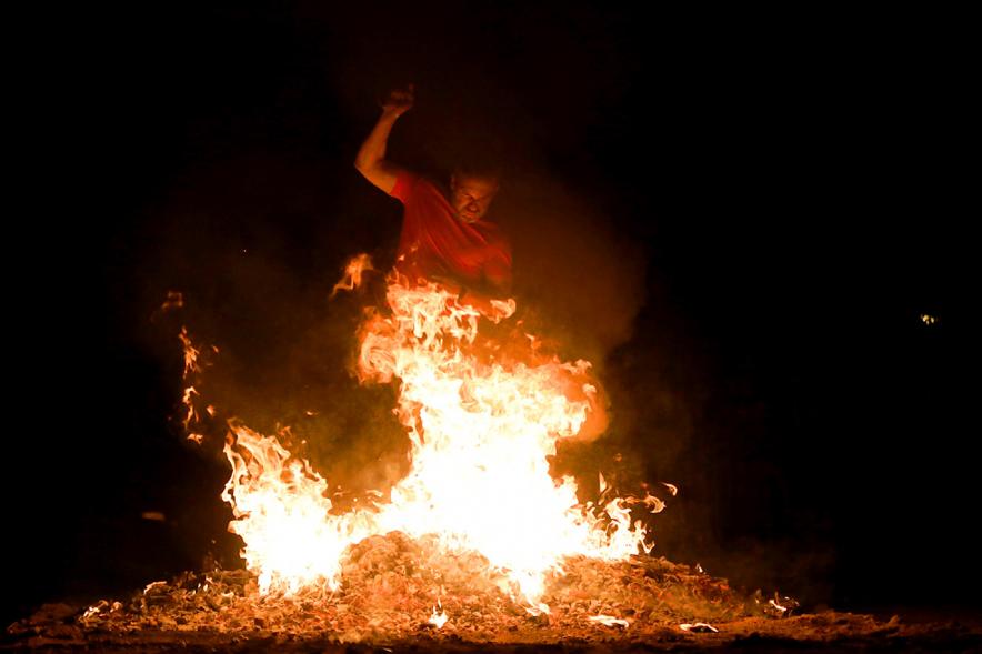 Noche de San Juan 2018 - Actividades y Hoguera de San Juan - Imagen de una gran llama de la hoguera y una persona saltándola.