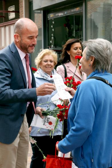 Concejal Cubián Martínez entregando claveles y programa de fiestas