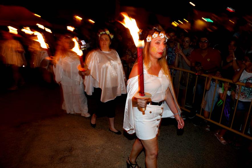Mujeres vestidas de blanco con coronas de flores y antorchas. Noche de San Juan 2019