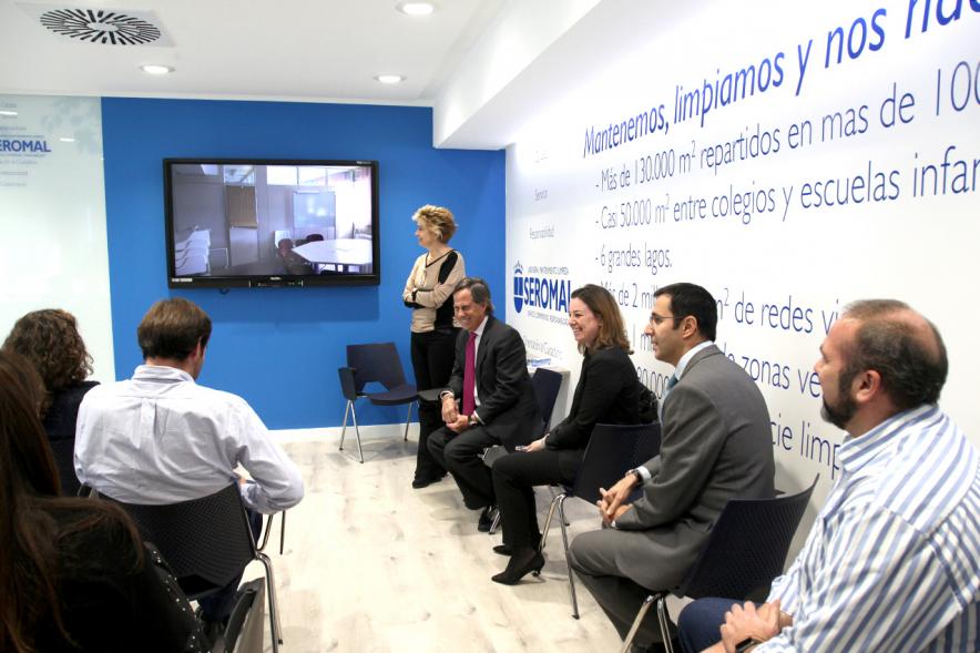 Visita Institucional a Seromal - Imagen del alcalde García de Vinuesa reunido con otras personas en una sala mirando un video en un pantalla de televisión.