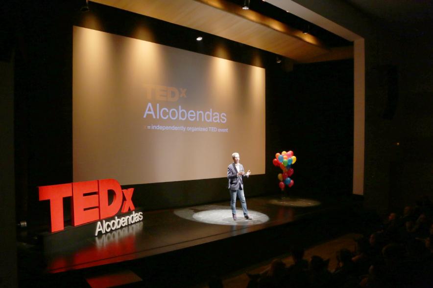 TEDx Alcobendas - Imagen del escenarios con un conferenciante y el nombre del evento. 