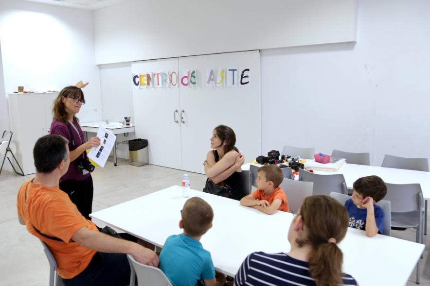 Taller de Fotografía con Niños en el Centro de Arte - Imagen de monitora del taller impartiendo clase a los niños participantes.
