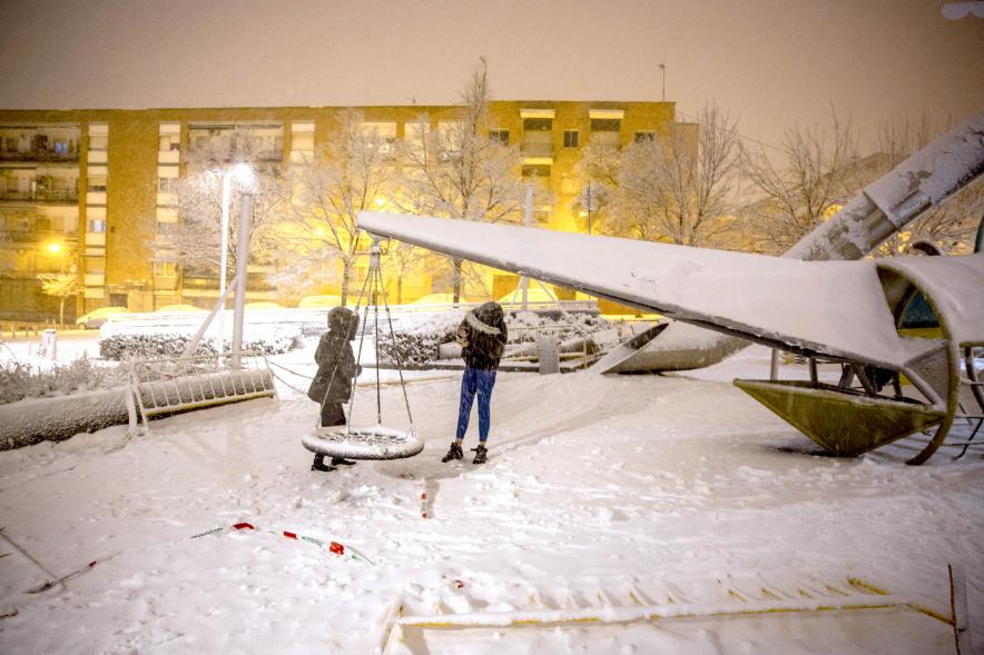 Jóvenes juegan en un columpio en la nieve