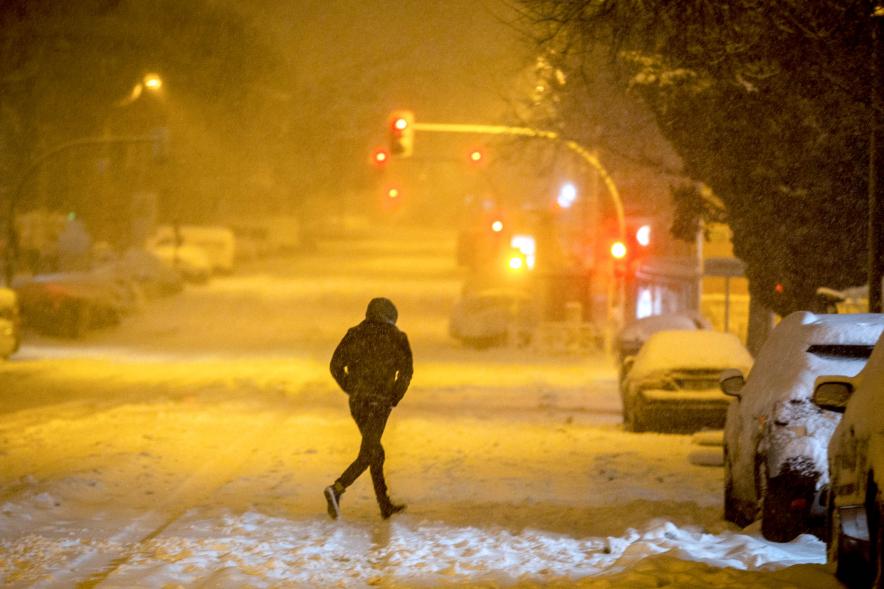 Persona cruzando una calle bloqueada por la nieve