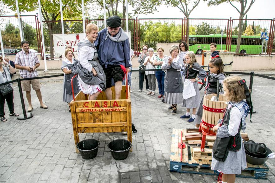 Fiesta de la Vendimia y Reparto de Migas Casa de Castilla la Mancha 2017 - Dos pisadores de uvas observados por una niña.