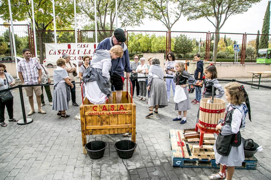 Fiesta de la Vendimia y Reparto de Migas Casa de Castilla la Mancha 2017 - Dos pisadores de uvas observados por una niña.