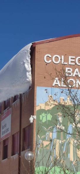 Fachada de colegio con lengua de nieve en el tejado