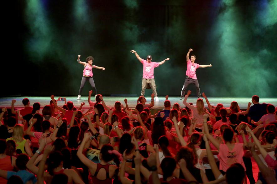 Masterclass Zumba Solidario AECC - Imagen profesores de zumba dando clase desde el escenario al público asistente.