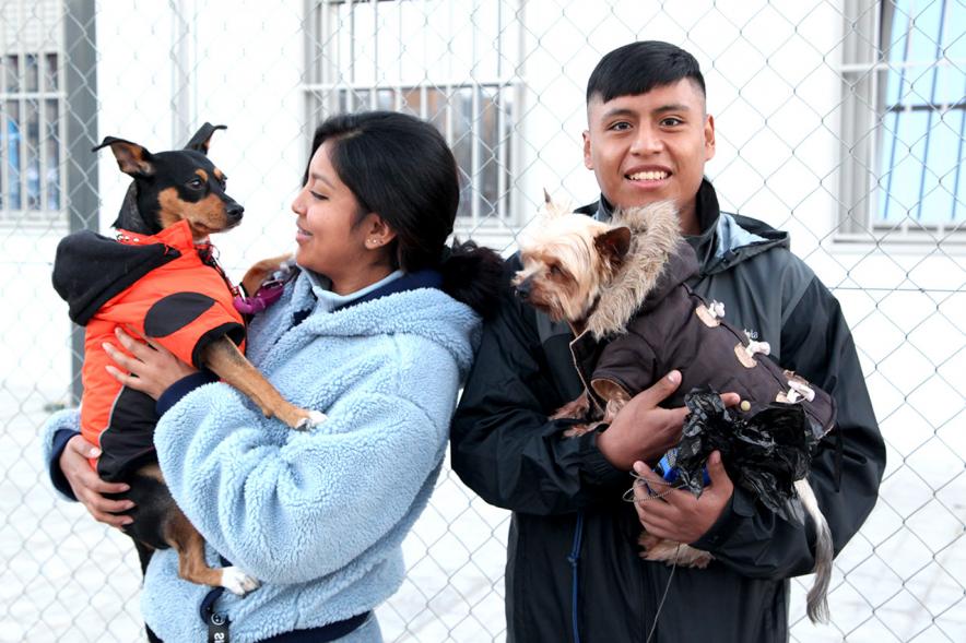 Bendición de Animales por San Antón en la Parroquia San Juan XXIII - Imagen de dos personas en el exterior con sus perros en brazos.