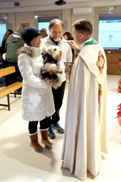 Bendición de Animales por San Antón en la Parroquia San Juan XXIII - Imagen de una familia acercando su perro para que el cura le bendiga.