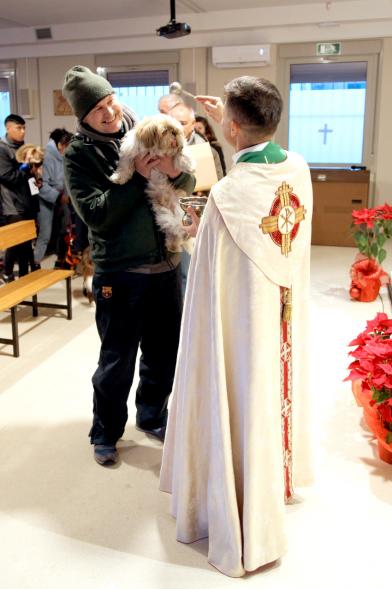 Bendición de Animales por San Antón en la Parroquia San Juan XXIII - Imagen de una persona acercando su perro para que el cura le bendiga.