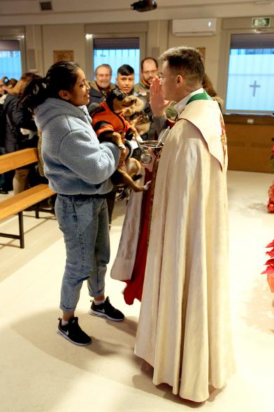 Bendición de Animales por San Antón en la Parroquia San Juan XXIII - Imagen de una persona acercando su perro para que el cura le bendiga.