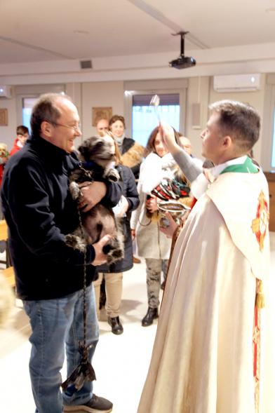 Bendición de Animales por San Antón en la Parroquia San Juan XXIII - Imagen de una persona acercando su perro para que el cura le bendiga.