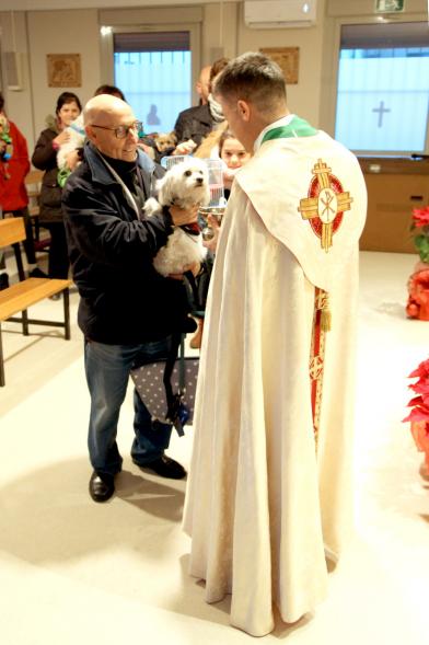 Bendición de Animales por San Antón en la Parroquia San Juan XXIII - Imagen de una familia acercando su perro para que el cura le bendiga.