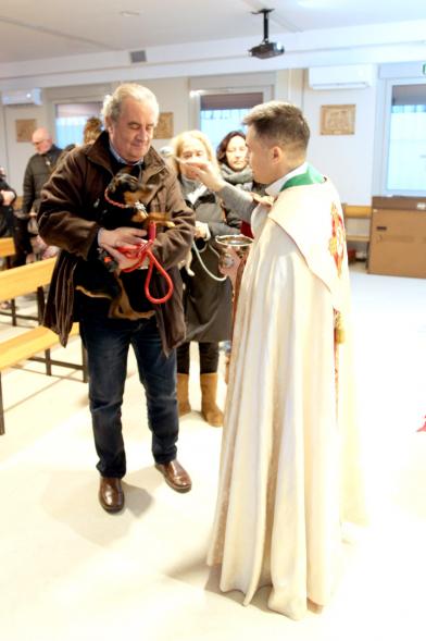 Bendición de Animales por San Antón en la Parroquia San Juan XXIII -Imagen de una persona acercando su perro para que el cura le bendiga.