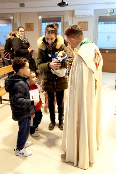 Bendición de Animales por San Antón en la Parroquia San Juan XXIII - Imagen de una familia acercando su perro para que el cura le bendiga.