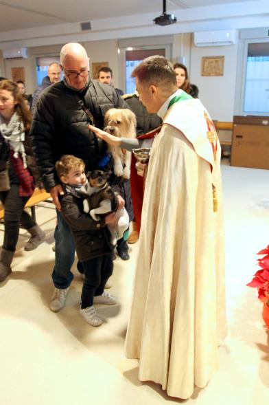 Bendición de Animales por San Antón en la Parroquia San Juan XXIII - Imagen de una familia acercando su perro para que el cura le bendiga.