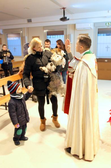 Bendición de Animales por San Antón en la Parroquia San Juan XXIII - Imagen de una familia acercando su perro para que el cura le bendiga.