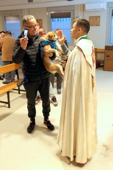 Bendición de Animales por San Antón en la Parroquia San Juan XXIII - Imagen de una persona acercando su perro para que el cura le bendiga.
