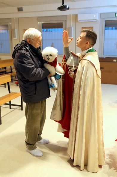 Bendición de Animales por San Antón en la Parroquia San Juan XXIII - Imagen de una persona acercando su perro para que el cura le bendiga.