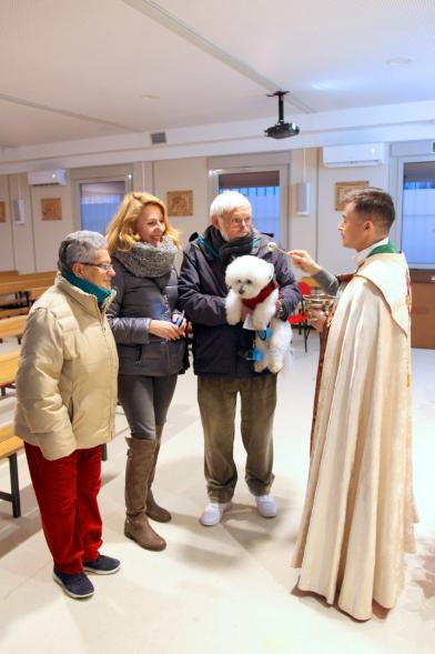 Bendición de Animales por San Antón en la Parroquia San Juan XXIII - Imagen de unas personas acercando su perro para que el cura le bendiga.