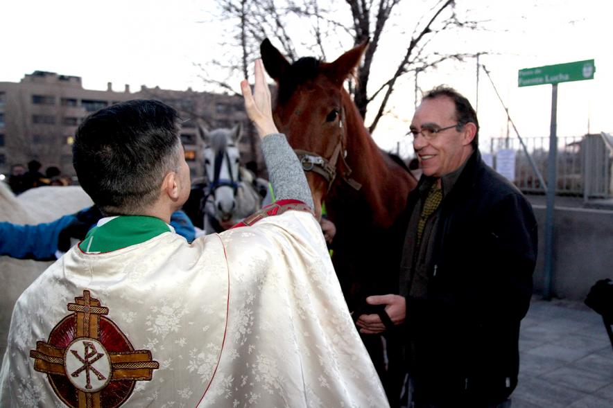 Bendición de Animales por San Antón en la Parroquia San Juan XXIII - Imagen del cura en el exterior de la iglesia bendiciendo a un caballo.