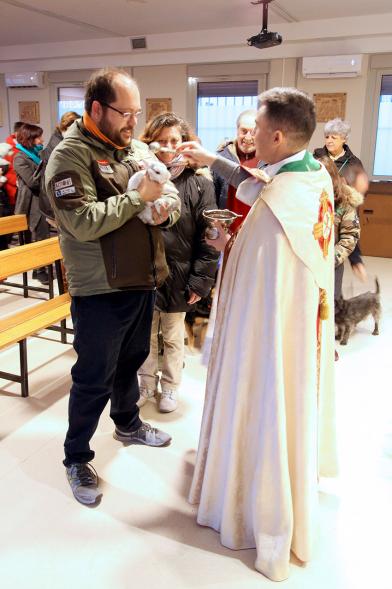 Bendición de Animales por San Antón en la Parroquia San Juan XXIII - Imagen de una persona acercando su perro para que el cura le bendiga.