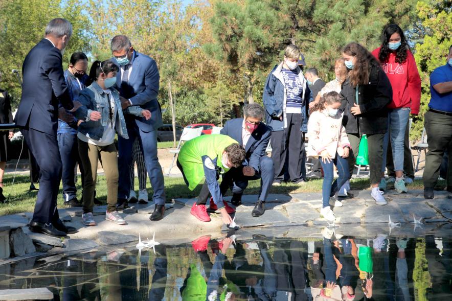 Día Internacional de la Paz - Imagen de los alumnos y alumnas de Apama y el resto de los presentes depositando grullas de origami en el estanque.