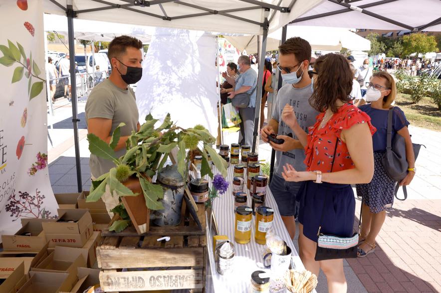 Mercado Ecológico en el Paseo Valdelasfuentes - Imagen de personas comprando en un puesto de miel.
