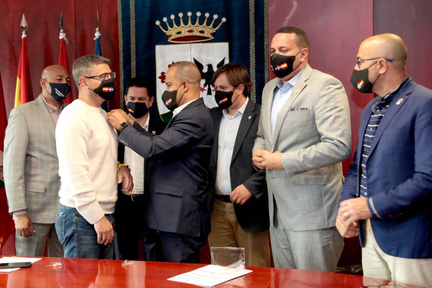  Bienvenida Delegación República Dominicana - Imagen de un miembro de la delegación República Dominicana colocando un insignia a una de las autoridades de Alcobendas.