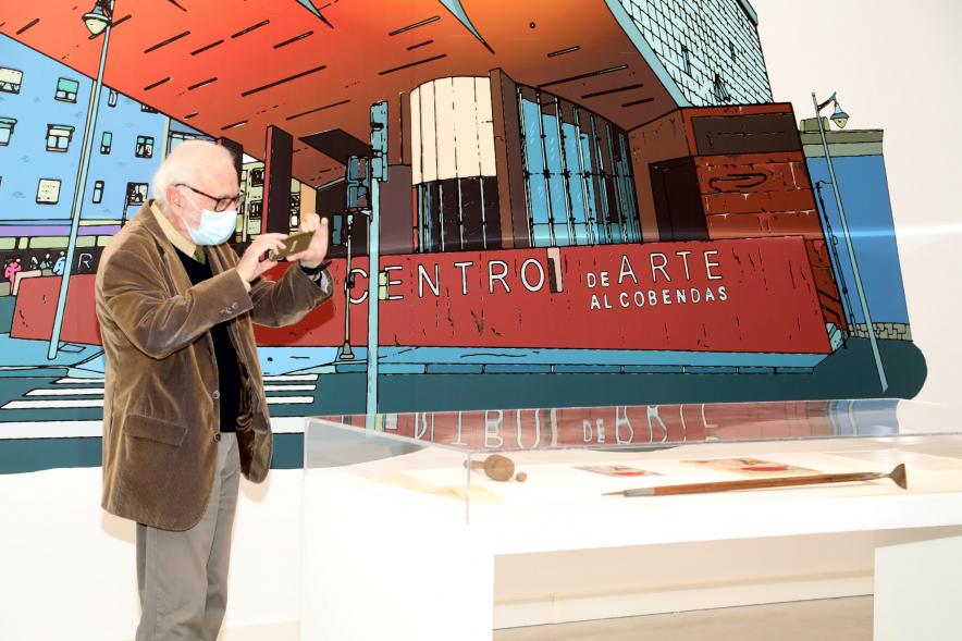 Inauguración Exposición "Miradas Tintinófilas" - Imagen de una persona haciendo una fotografía con su móvil a uno de los objetos de la exposición.